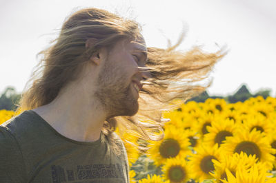 Close-up of young woman with sunflower on field against clear sky