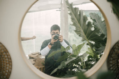 Reflection of man photographing through camera