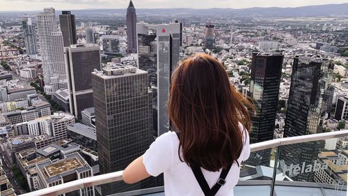 Rear view of woman standing by buildings in city