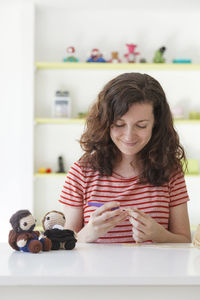 Portrait of a smiling young woman with toy on table