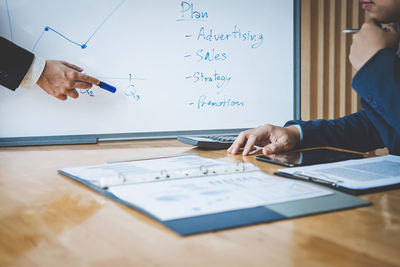 Cropped hands of businessmen working at desk in office