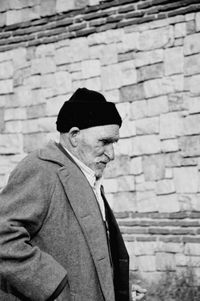 Side view of man standing against brick wall