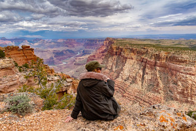 Rear view of woman sitting on rock