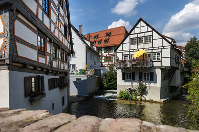 Houses by river in town against sky