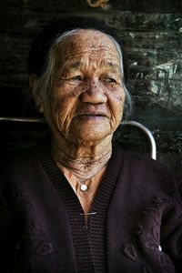 Close-up of senior woman looking away sitting against wall