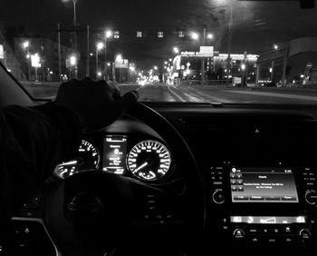 Man driving car on illuminated street at night