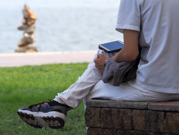 Low section of man using mobile phone while sitting on seat