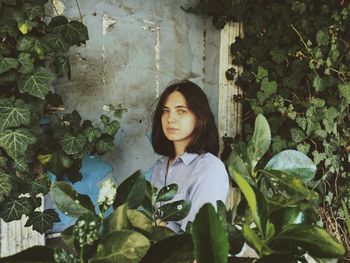 Young woman standing by ivy on tree