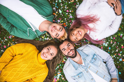 High angle view of cheerful friends lying on grassy land