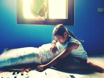 Full length of girl sitting on bed