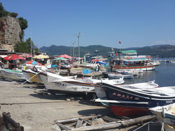 Boats moored at harbor against clear blue sky