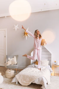 Woman with arms raised on bed at home