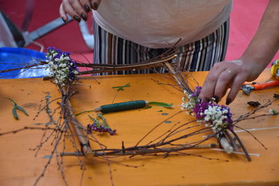 Midsection of florist cutting flowers on table in shop