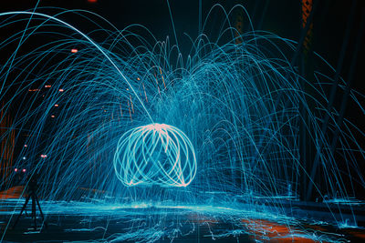Low section of man spinning wire wool at night