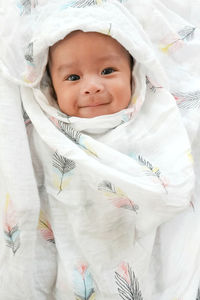 A cute 3 month asian baby smiling and happy with swaddled.