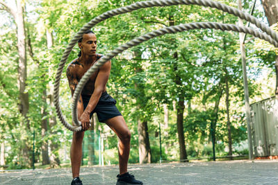 Full length of shirtless athlete exercising on footpath