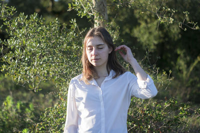 Portrait of beautiful young woman standing against plants