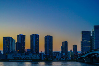 Modern buildings in city against sky during sunset