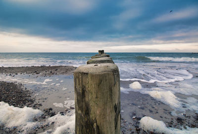 Wooden posts on beach against sky