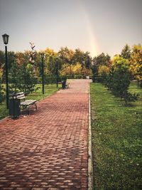 Footpath in park against sky during sunset