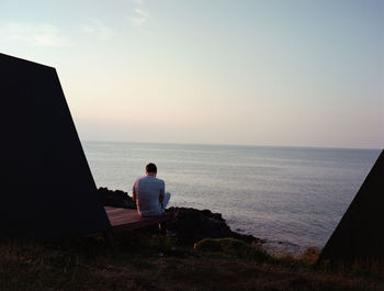 Rear view of man looking at sea against sky