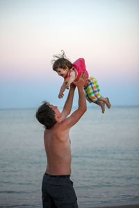 Father playing with daughter at beach