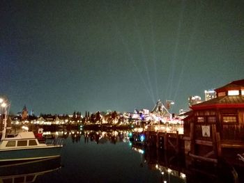 Boats moored at harbor against clear sky at night