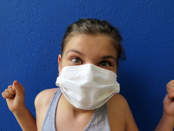 Portrait of teenage girl against blue wall