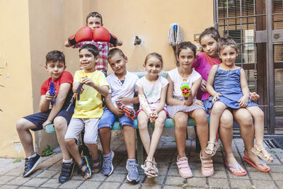 Group of little boys of different ages sitting having fun and playing together in a courtyard