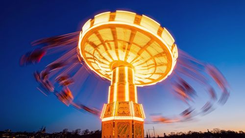 Long exposure low angle view of carousel against blue evening sky