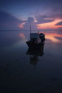 Fishing boat on sea against sky during sunset