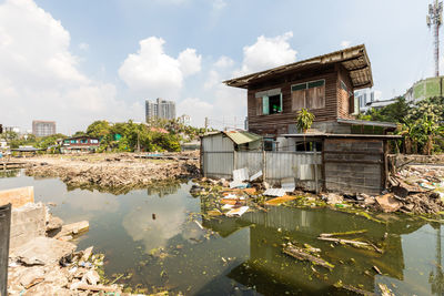 Houses by lake and buildings against sky