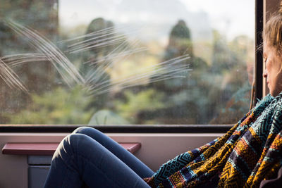 Low section of woman sitting on window