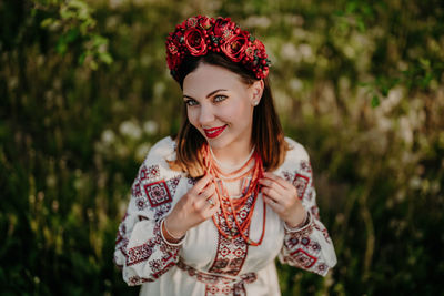 Portrait of young woman standing against plants