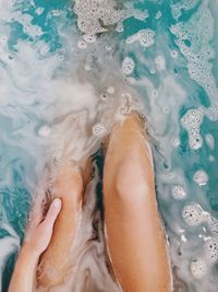 Low section of woman legs sitting in bathtub