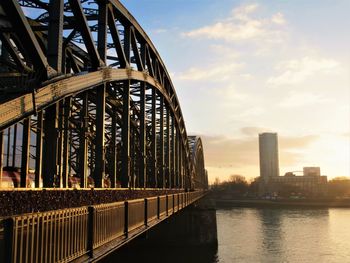 Bridge over river by buildings against sky in city