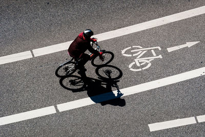 High angle view of man cycling on bicycle lane during sunny day