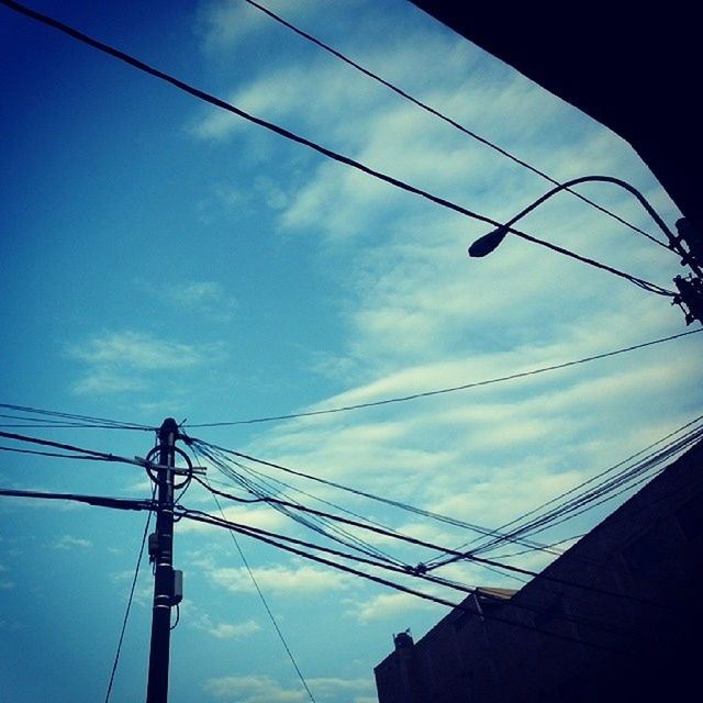 power line, low angle view, electricity pylon, electricity, power supply, cable, connection, sky, fuel and power generation, technology, power cable, blue, silhouette, cloud - sky, cloud, built structure, outdoors, no people, architecture, complexity