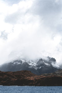 Scenic view of sea by snowcapped mountains against sky