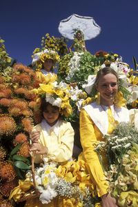 Portrait of woman with girl sitting amidst flowers during parade
