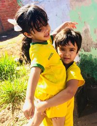 Portrait of brother carrying sister in yard