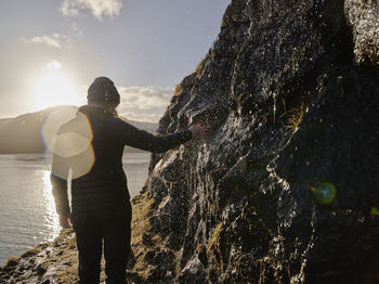 Woman touching water streaming over rocks in the faroe islands