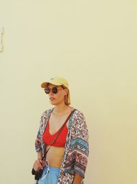 Portrait of young woman standing against pink background