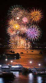 Firework display over sea against sky at night