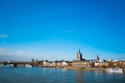 Distant view of great st martin church by rhine river against blue sky