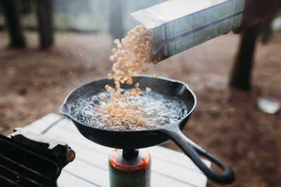Pasta being poured in cooking utensil at campsite