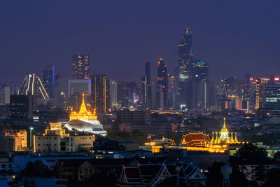 Illuminated buildings in city against sky at night