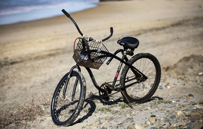 Bicycle parked on sand at beach