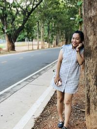 Full length of young woman using phone while standing on road