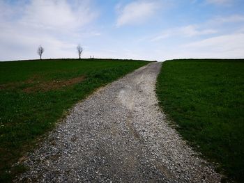 Road amidst field against sky